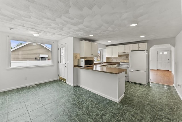 76 Choctaw Dr, Wareham, MA 02532 - kitchen with white appliances, a sink, dark countertops, decorative backsplash, and a peninsula