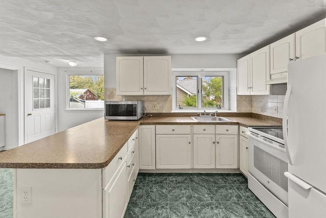 76 Choctaw Dr, Wareham, MA 02532 - kitchen featuring white appliances, a sink, under cabinet range hood, dark countertops, and a peninsula