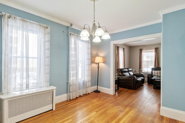 interior space featuring hardwood / wood-style floors, crown molding, radiator heating unit, and a chandelier