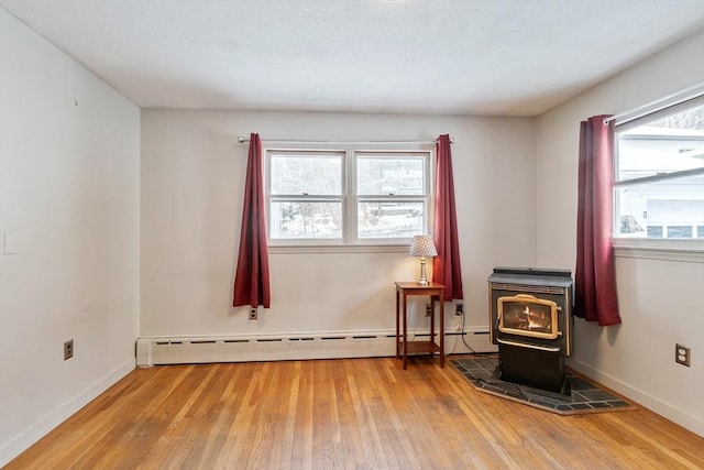 interior space featuring hardwood / wood-style flooring, plenty of natural light, a baseboard radiator, and a wood stove