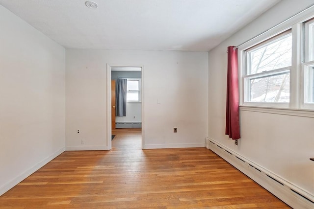 unfurnished room featuring light hardwood / wood-style floors and a baseboard heating unit