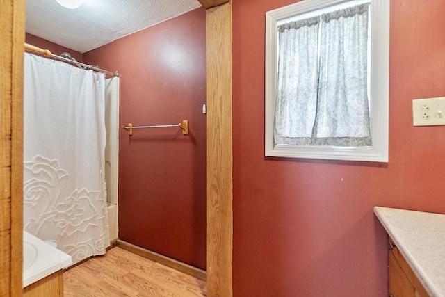 bathroom featuring hardwood / wood-style flooring, shower / tub combo with curtain, vanity, and a textured ceiling