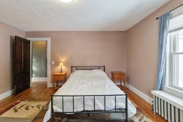 bedroom featuring radiator and hardwood / wood-style floors