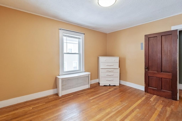 spare room featuring crown molding, radiator heating unit, and light hardwood / wood-style flooring