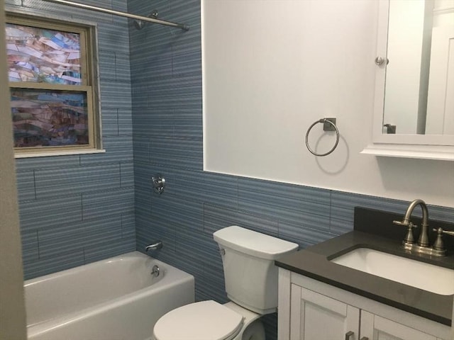 full bathroom with vanity, tiled shower / bath, tile walls, and toilet