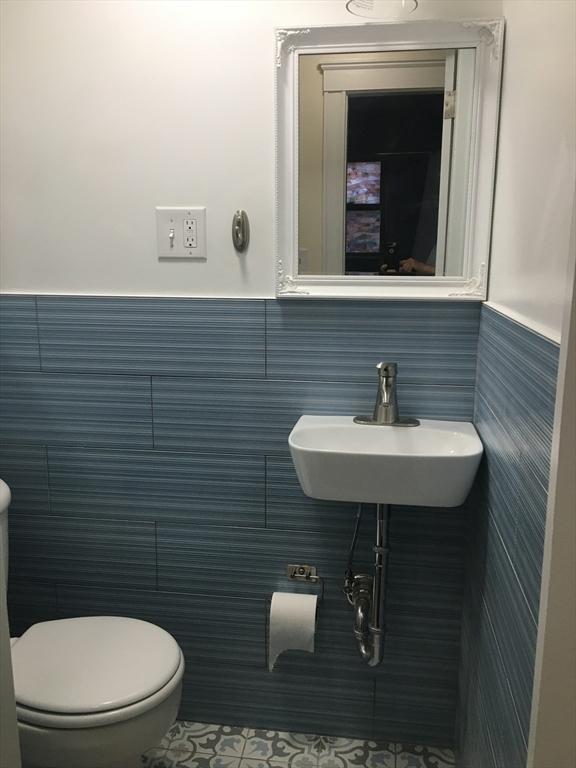 bathroom with tile walls, sink, tile patterned floors, and toilet