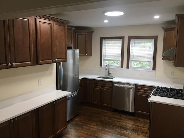 kitchen with appliances with stainless steel finishes, sink, dark wood-type flooring, and dark brown cabinetry