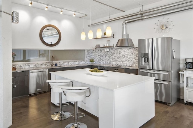 kitchen featuring decorative backsplash, dark wood finished floors, appliances with stainless steel finishes, and a kitchen island