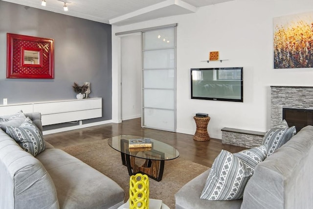 living area with track lighting, a fireplace, baseboards, and wood finished floors