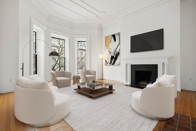 living room featuring a fireplace with flush hearth, baseboards, hardwood / wood-style floors, and crown molding
