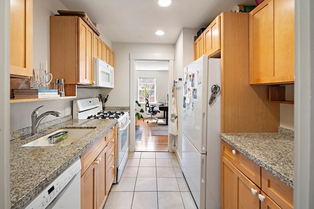 kitchen with white appliances, light stone counters, sink, and light tile patterned flooring