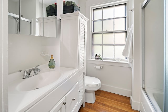 full bathroom with wood-type flooring, toilet, bath / shower combo with glass door, and vanity