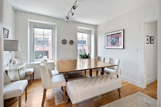 dining space with light wood-type flooring and rail lighting