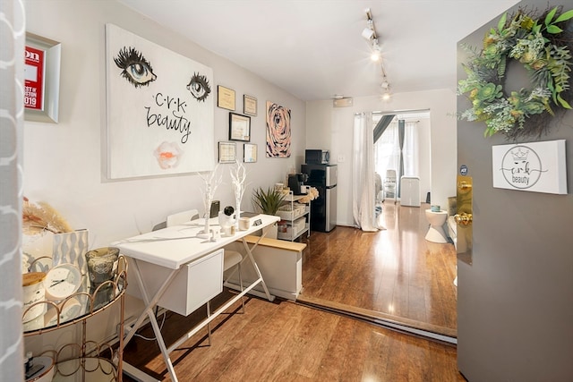 home office with rail lighting and hardwood / wood-style flooring