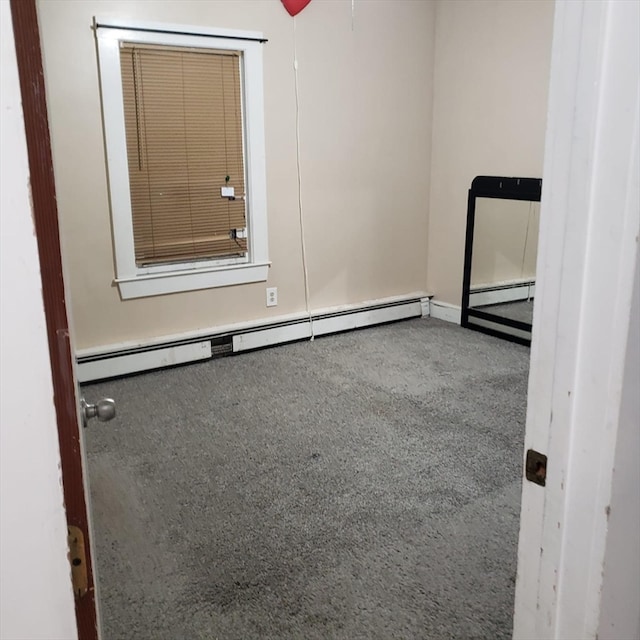 empty room featuring baseboard heating and carpet