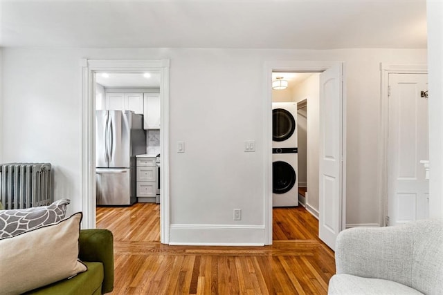 12 Lindall Pl Unit 3, Boston, MA 02114 - living area featuring stacked washing machine and dryer, radiator heating unit, wood finished floors, and baseboards