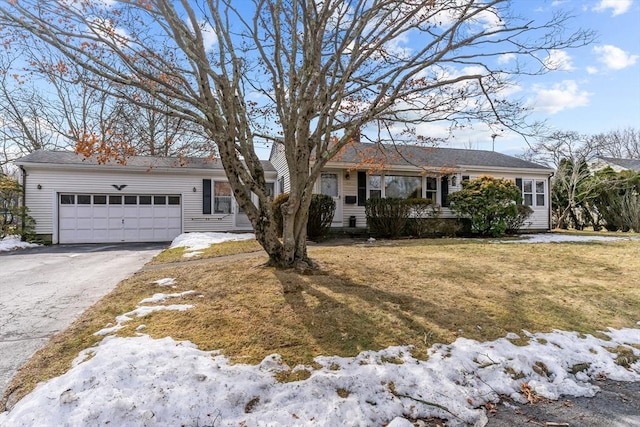 ranch-style home featuring a garage, a lawn, and aphalt driveway