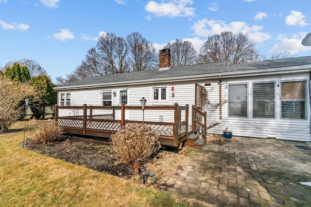 back of property with a wooden deck, a lawn, a chimney, and a patio