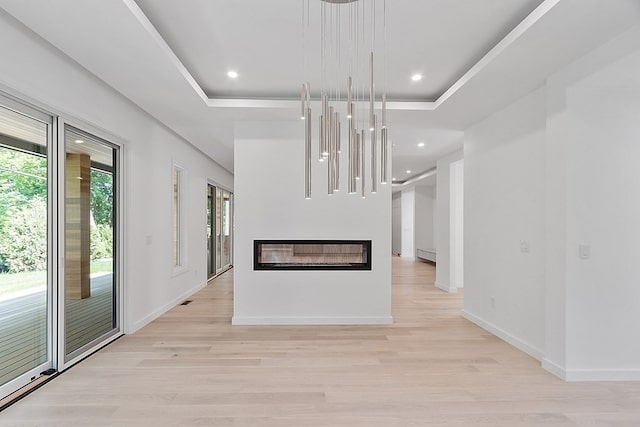 kitchen featuring light hardwood / wood-style flooring, hanging light fixtures, an inviting chandelier, and a tray ceiling