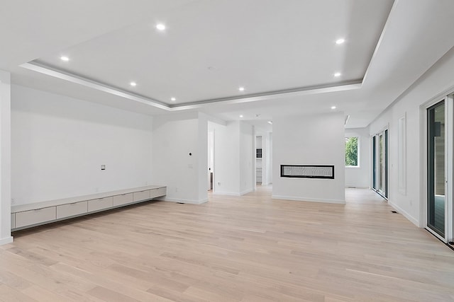 unfurnished living room with light hardwood / wood-style flooring and a raised ceiling