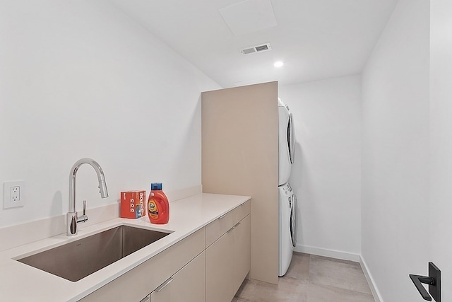 interior space featuring cabinets, light tile floors, sink, and stacked washer and dryer