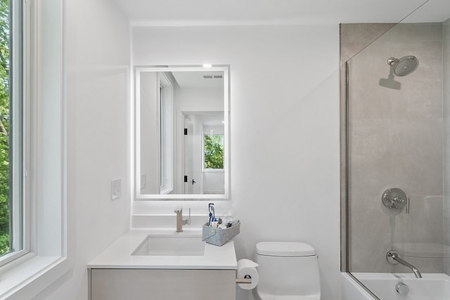 full bathroom featuring toilet, a wealth of natural light, tiled shower / bath combo, and vanity