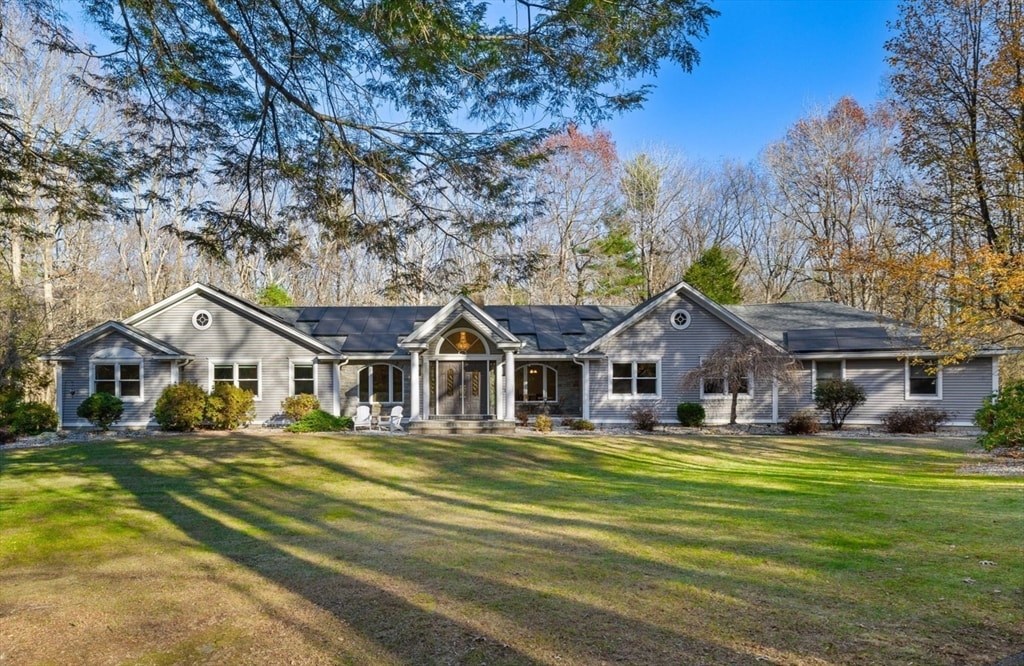 ranch-style home featuring solar panels and a front lawn