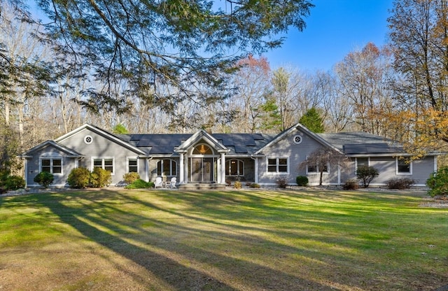 ranch-style home featuring solar panels and a front lawn