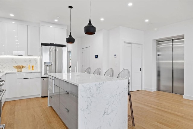 kitchen with elevator, white cabinetry, decorative light fixtures, and modern cabinets