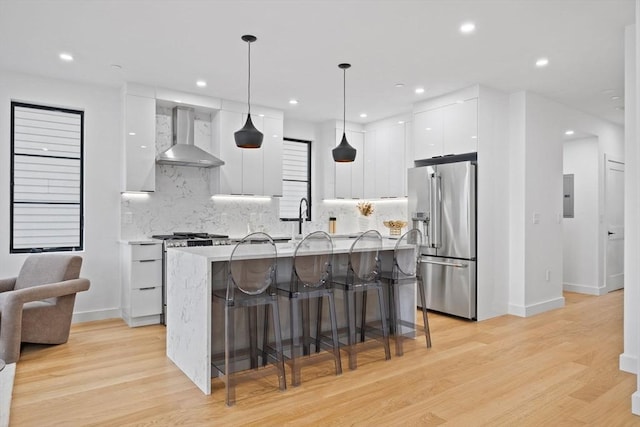 kitchen with decorative light fixtures, appliances with stainless steel finishes, white cabinets, modern cabinets, and wall chimney exhaust hood