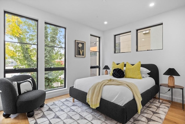 bedroom with light wood-style floors, recessed lighting, multiple windows, and baseboards