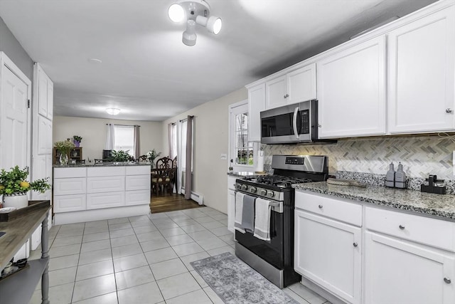 kitchen featuring stainless steel appliances, tasteful backsplash, a baseboard radiator, white cabinets, and light tile patterned floors