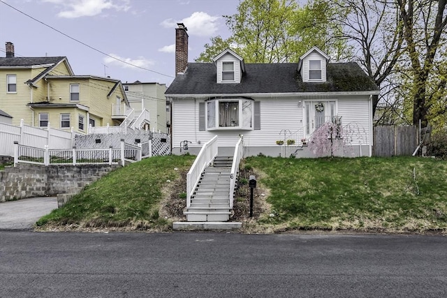 view of front of property featuring stairway, a chimney, fence, and a shingled roof