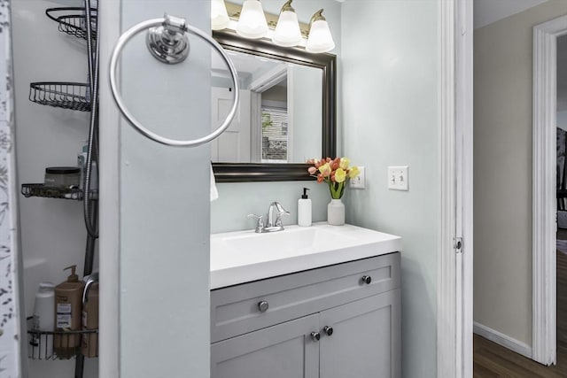 bathroom with wood finished floors, vanity, and baseboards