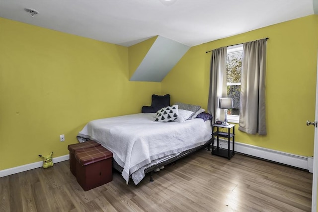 bedroom featuring baseboard heating, wood finished floors, and baseboards