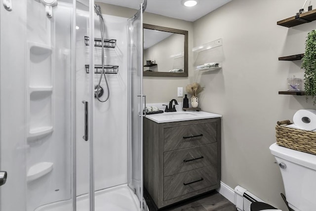 bathroom with a shower stall, baseboard heating, toilet, baseboards, and vanity