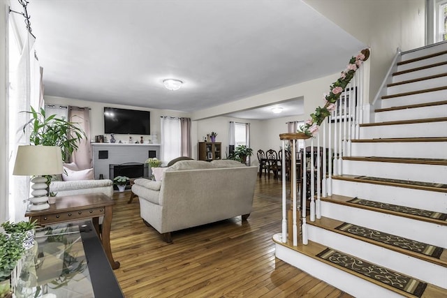living area with stairway, a fireplace, and wood finished floors