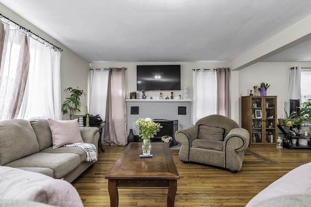 living area with a brick fireplace and wood finished floors