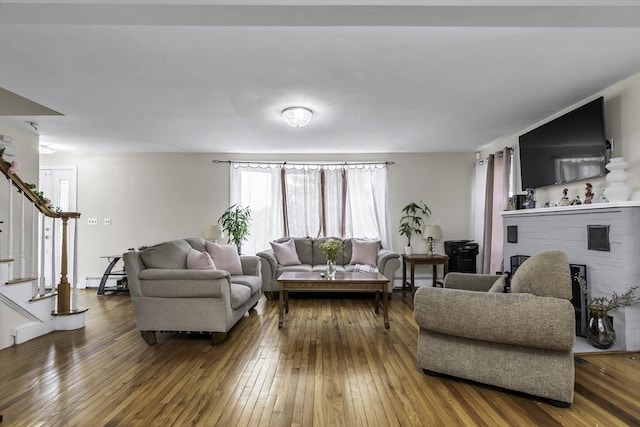 living area with hardwood / wood-style flooring, stairs, a fireplace, and baseboard heating