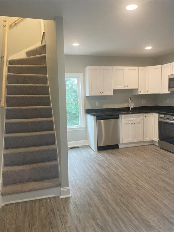 15 Forest St, Whitman, MA 02382 - kitchen with stainless steel appliances, wood finished floors, white cabinetry, and recessed lighting