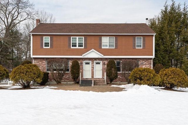 colonial house with a chimney and brick siding