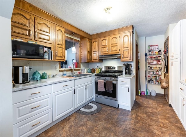 kitchen with light countertops, under cabinet range hood, stainless steel range with gas cooktop, black microwave, and a sink