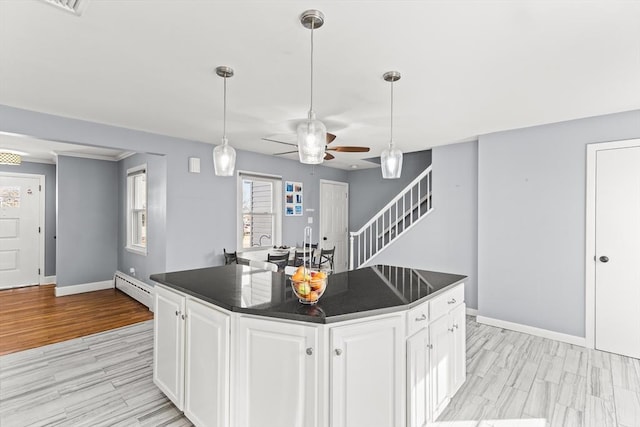 kitchen with dark countertops, white cabinets, light wood finished floors, and a baseboard radiator