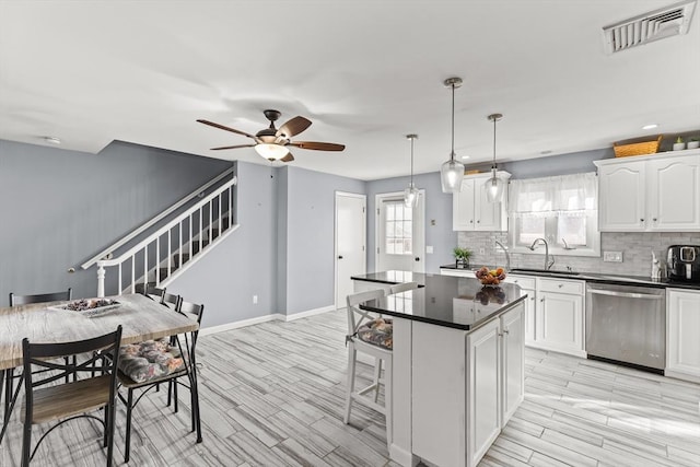 kitchen featuring visible vents, a sink, stainless steel dishwasher, dark countertops, and backsplash