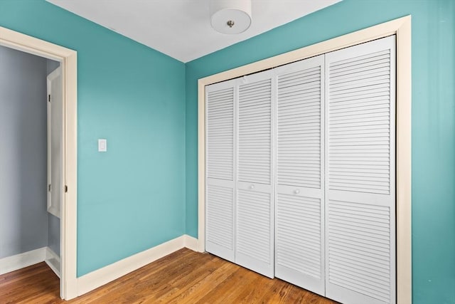 unfurnished bedroom featuring wood finished floors, a closet, and baseboards