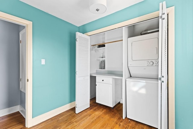 laundry room with laundry area, stacked washer and clothes dryer, baseboards, and light wood-style floors