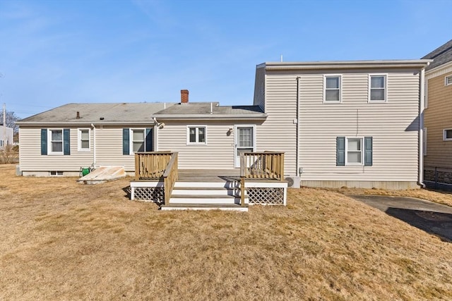 back of property featuring a lawn, a chimney, and a deck