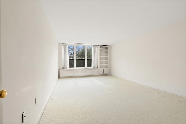 carpeted empty room featuring baseboards