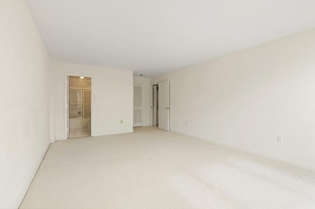 unfurnished bedroom featuring baseboards, light carpet, and ensuite bath