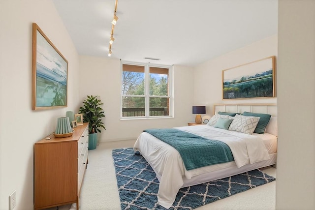 bedroom with track lighting, visible vents, and carpet